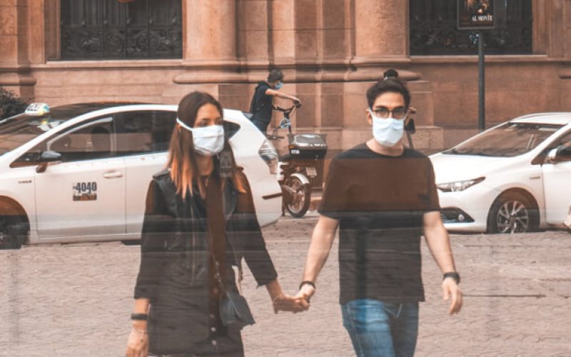 Couple holding hands walking and wearing surgical masks. Medazur Medical Clinic in Leytonstone.