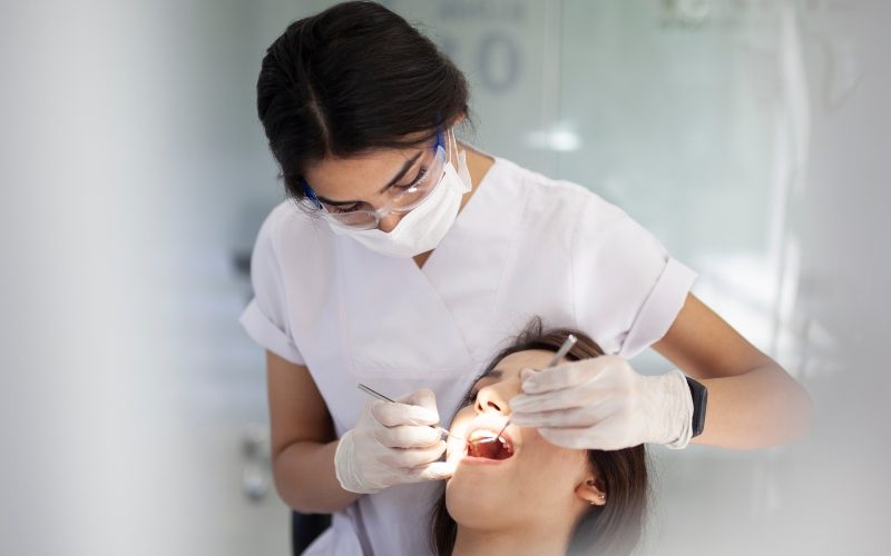 Female dental hygienist performing clean-up on female patient.