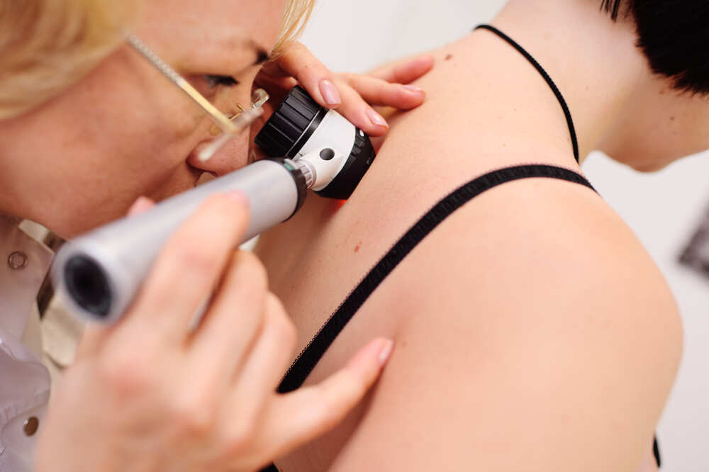 Female dermatologist examines female patient's skin in her back. Medazur Medical Clinic in Leytonstone.