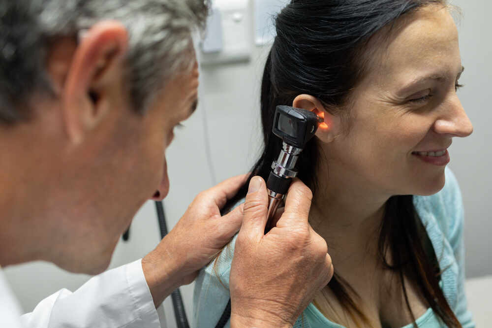 Male doctor inspects female patient's ear. Medazur Medical Clinic in Leytonstone.