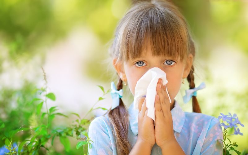 Young girl with spring allergy blows her nose with tissue. Medazur Medical Clinic.